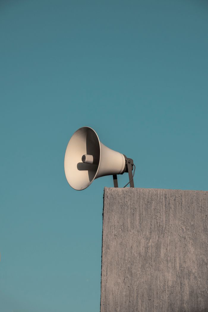 A megaphone mounted atop a concrete structure under a clear blue sky, minimalistic view.