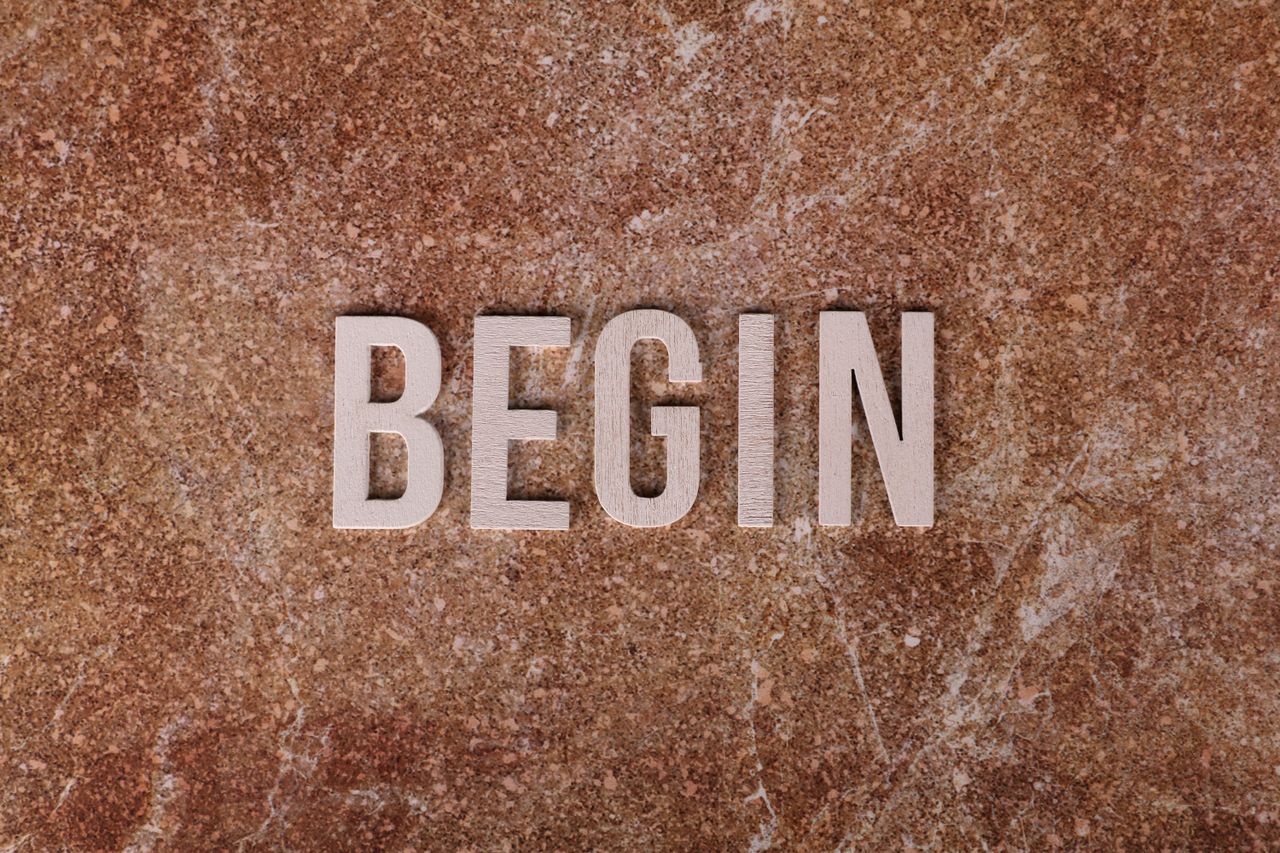 Text 'BEGIN' on a textured stone background, symbolizing a fresh start.