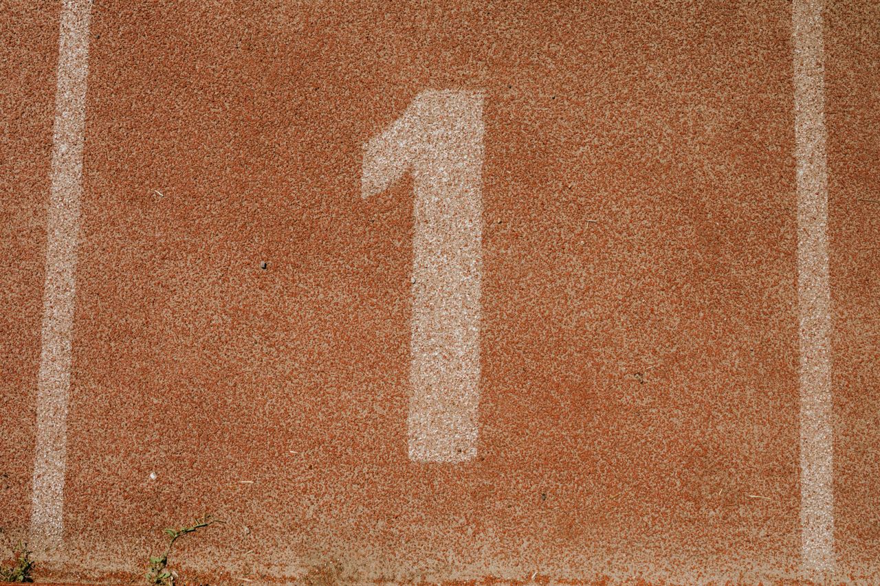 Close-up image of number one lane on a running track, symbolizing first place.